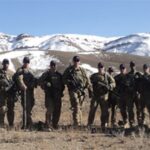 Members of the US Military posing in front of snow capped hills