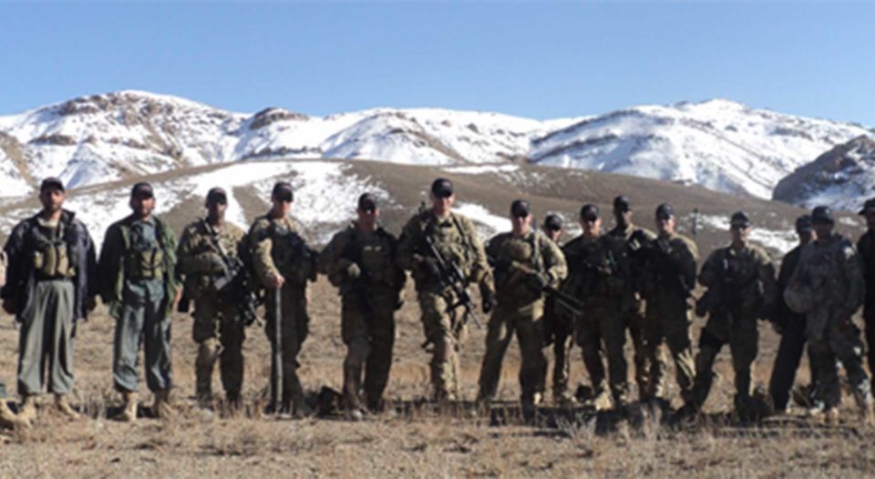 Members of the US Military posing in front of snow capped hills