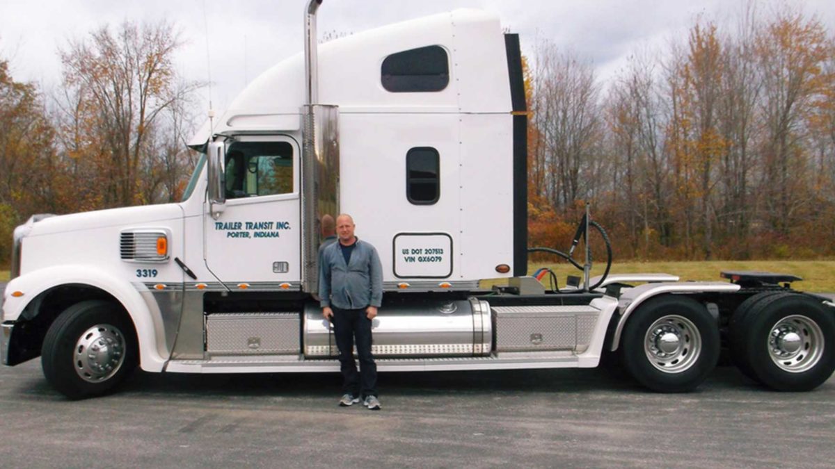 Trailer Transit Inc. | A man standing in front of a white semi truck.