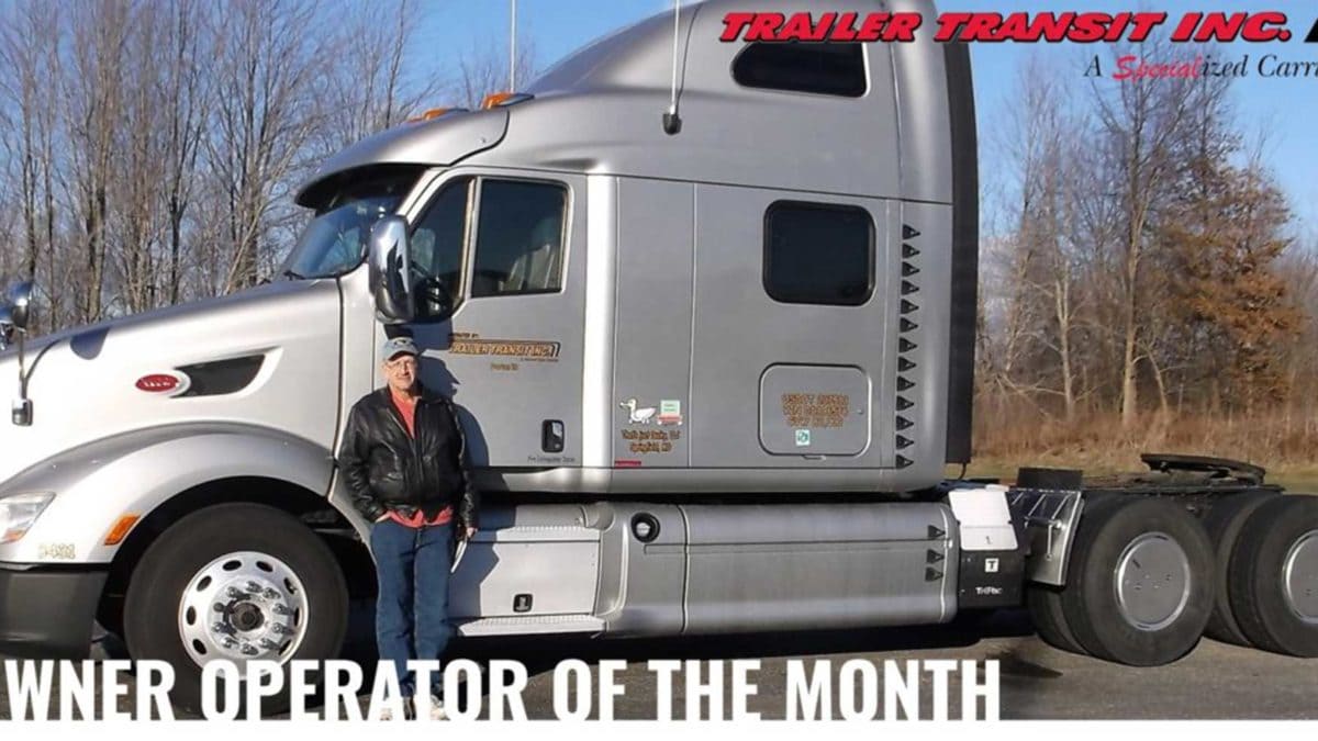 Trailer Transit Inc. | A man standing in front of a semi truck with the words power operator of the month.