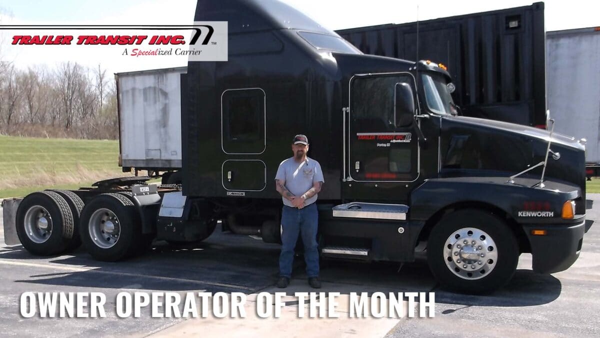 Trailer Transit Inc. | A man standing in front of a black semi truck.