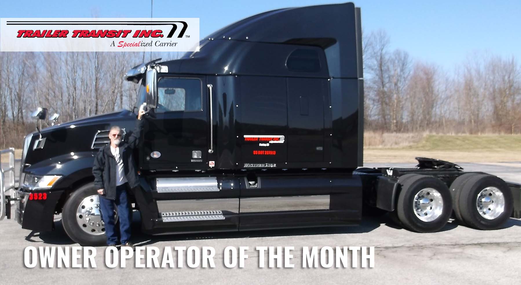Trailer Transit Inc. | A man standing in front of a black semi truck with the words owner operator of the month.