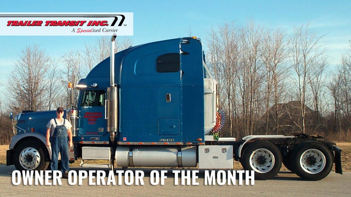 Trailer Transit Inc. | A man standing in front of a semi truck with the words owner operator of the month.