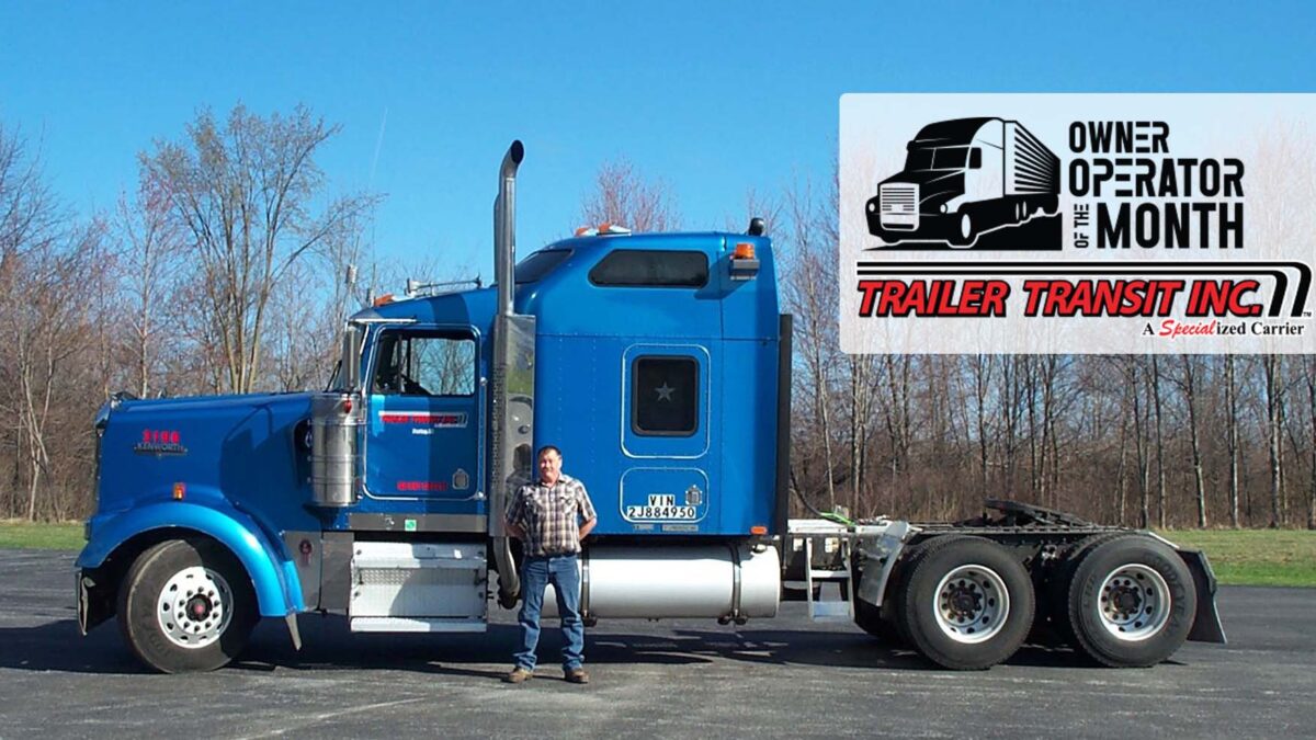 Trailer Transit Inc. | An award-winning owner operator of the month standing in front of a semi truck.