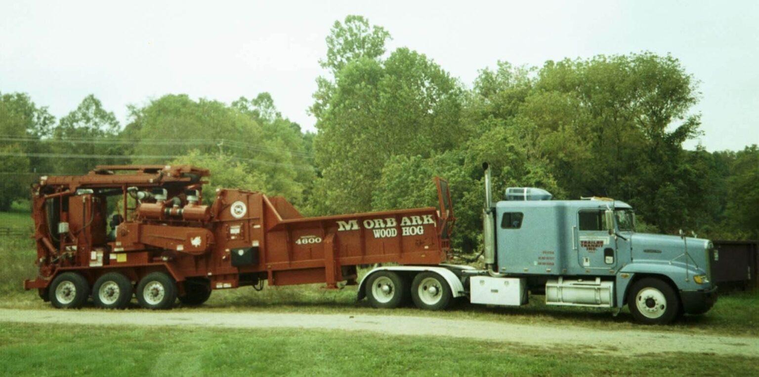 Old photo os a Trailer Transit, Inc truck hauling machinery