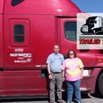 Trailer Transit Inc. | Two people standing in front of a red semi truck.