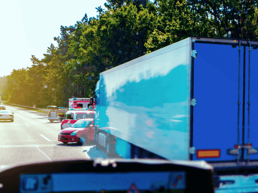 Trailer Transit Inc. | A traffic accident involving a truck and a car on a highway, with emergency vehicles present, shows the benefits of dash cams for owner-operators. Trees in the background highlight the scene.