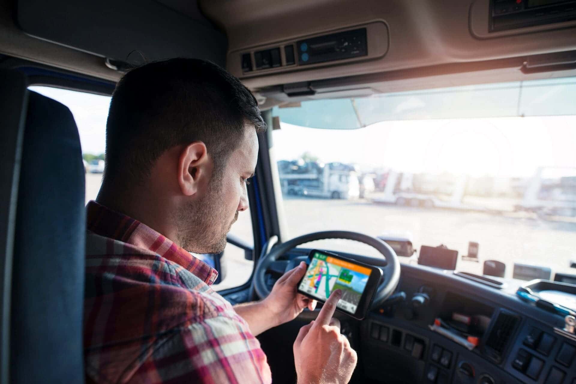 Professional middle aged trucker using truck gps navigation to t owner operator using GPS inside cab