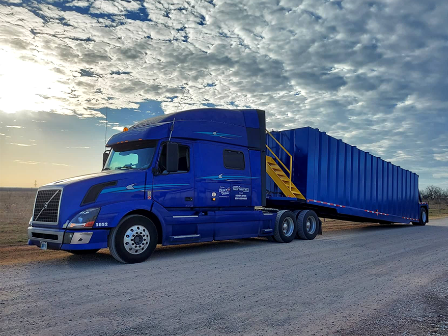 Blue truck and trailer against beautiful cloudy sky near dusk