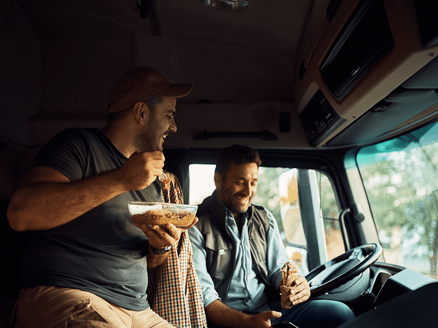 driver and friend enjoying meal in truck on the road