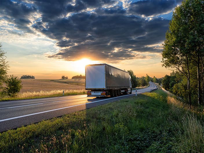 truck and trailer on the road with sunrise in the background