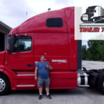 Trailer Transit Inc. | The Owner Operator of the Month proudly stands in front of his red semi truck.