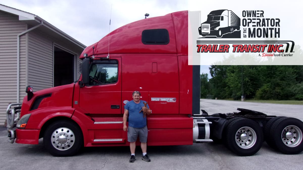 Trailer Transit Inc. | The Owner Operator of the Month proudly stands in front of his red semi truck.