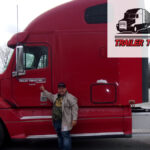 Trailer Transit Inc. | The Owner Operator of the Month proudly stands next to a red semi truck.