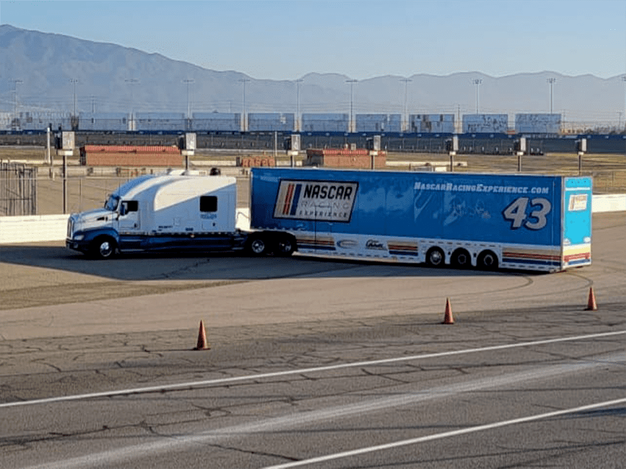 Trailer Transit Inc. | A semi truck is parked on a track with mountains in the background.