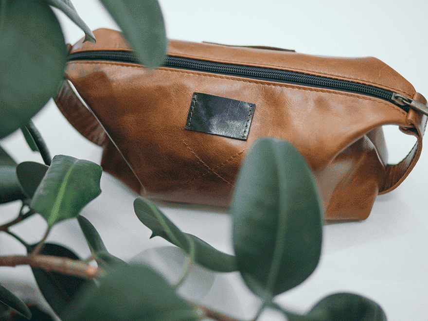 Trailer Transit Inc. | A brown leather bag sitting on a table next to a plant, with an owner nearby.