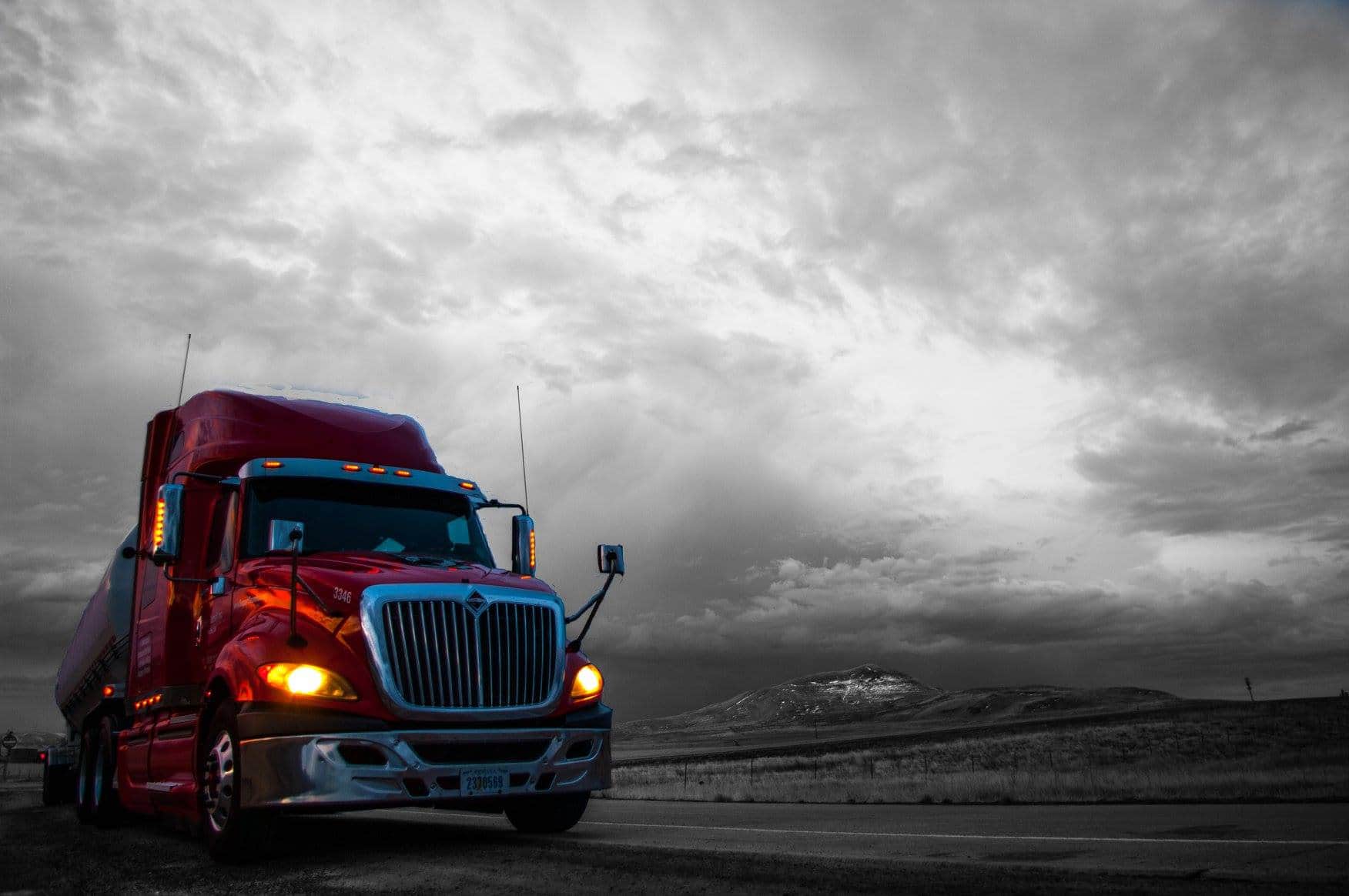 Trailer Transit Inc. | A red owner operator semi truck is driving down the road.