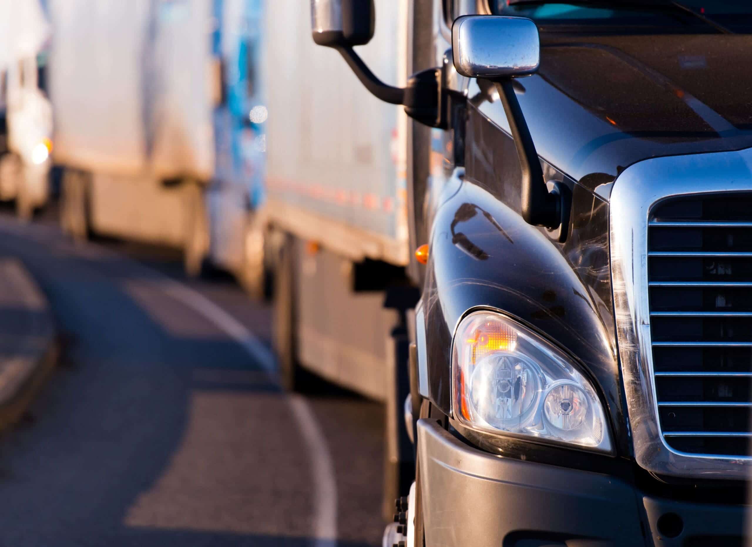 Heart-of-Trucking-Innovation Trailer Transit Inc. | Several trucks driving down a road, close up view.