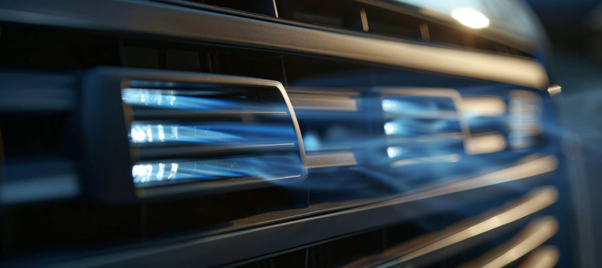 Close up of black plastic car air conditioning vent with smooth flowing blue air streams Trailer Transit Inc. | Close-up of a vehicle's AC vents blowing cold blue illustrated air.