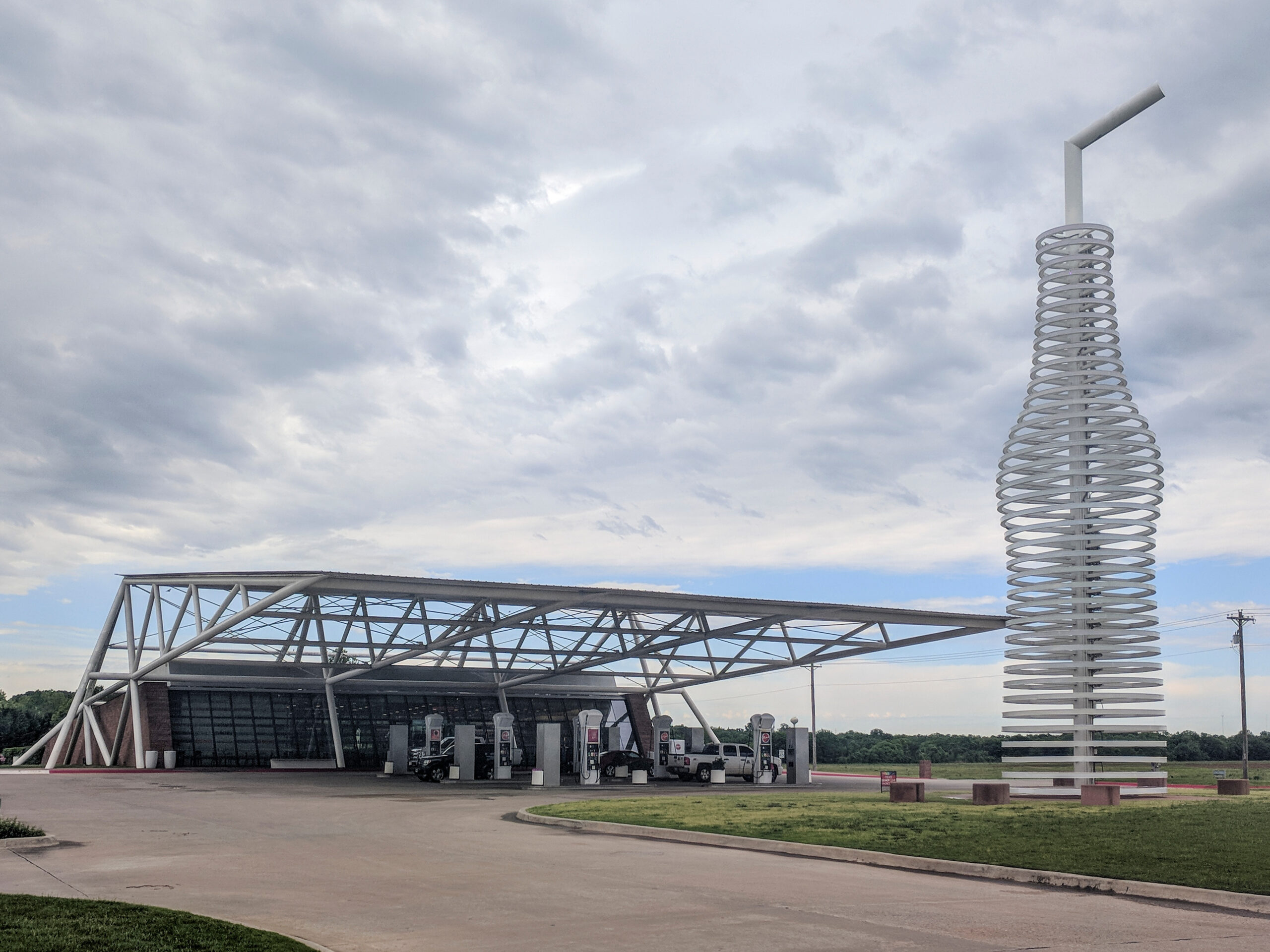 Trailer Transit Inc. | A modern gas station with a large roof structure and a tall bottle-shaped sculpture, Pops 66 Soda Ranch