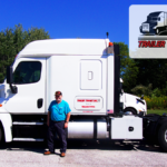 Trailer Transit Inc. | Owner Operator of the Month of July, Terry, stands in front of his white semi-truck. The top right corner displays "Owner Operator of the Month" alongside the "Trailer Transit Inc." logo. Trees are visible in the background, highlighting the prestige of owner operator driving jobs.