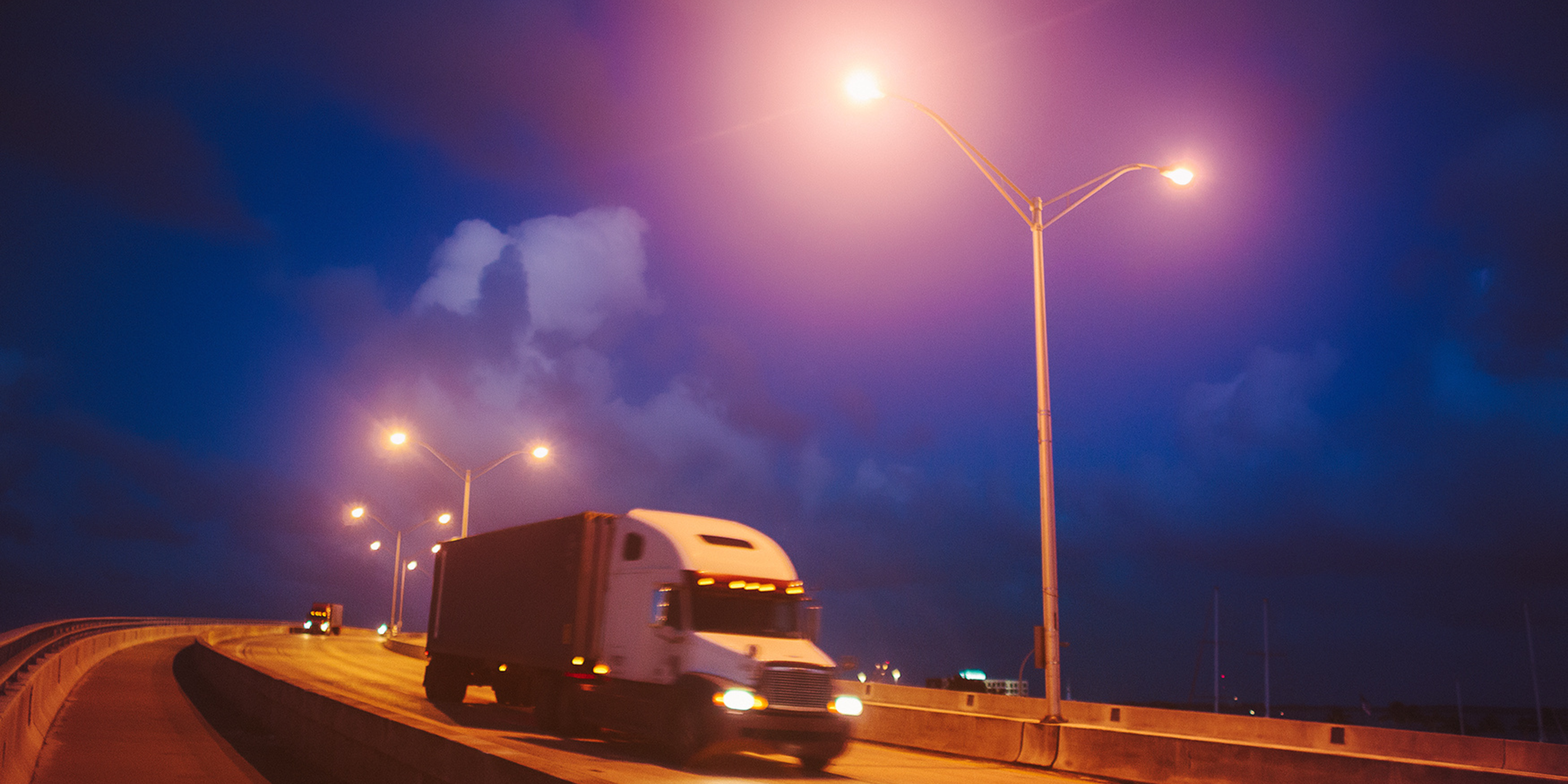 7 Trailer Transit, Inc | semi trucks driving in the late evening with street lights on