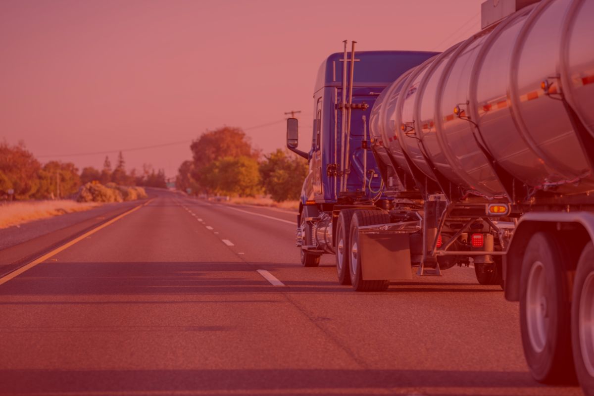 3 Trailer Transit Inc. | A Power-Only Trucking tanker hauling water drives down an empty highway, with trees and power lines lining the roadside beneath a clear sky.