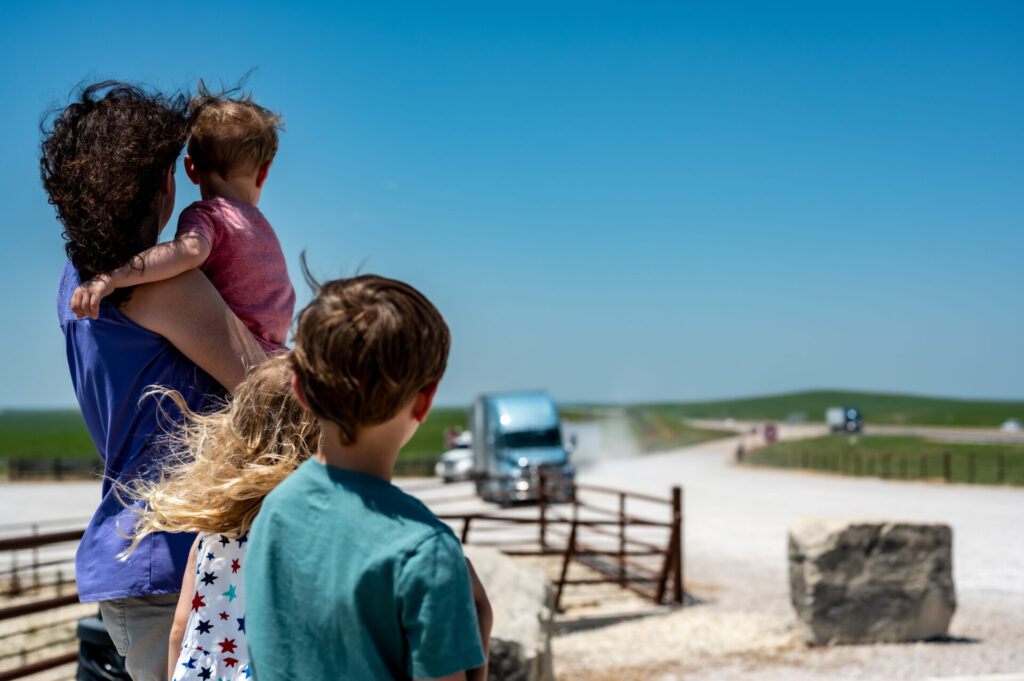 Trailer Transit Inc. | A woman with three small children awaits the arrival of her husband, a power only driver, as he drives his rig up their dirt road after a hauling job.