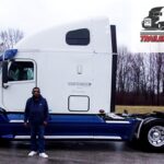 Trailer Transit Inc. | Owner Operator, Nathaniel, stands in front of his blue and white semi-truck, representing Owner Operator trucking in Indiana. The image features "Owner Operator of the Month" and "Trailer Transit Inc." logos in the corner.