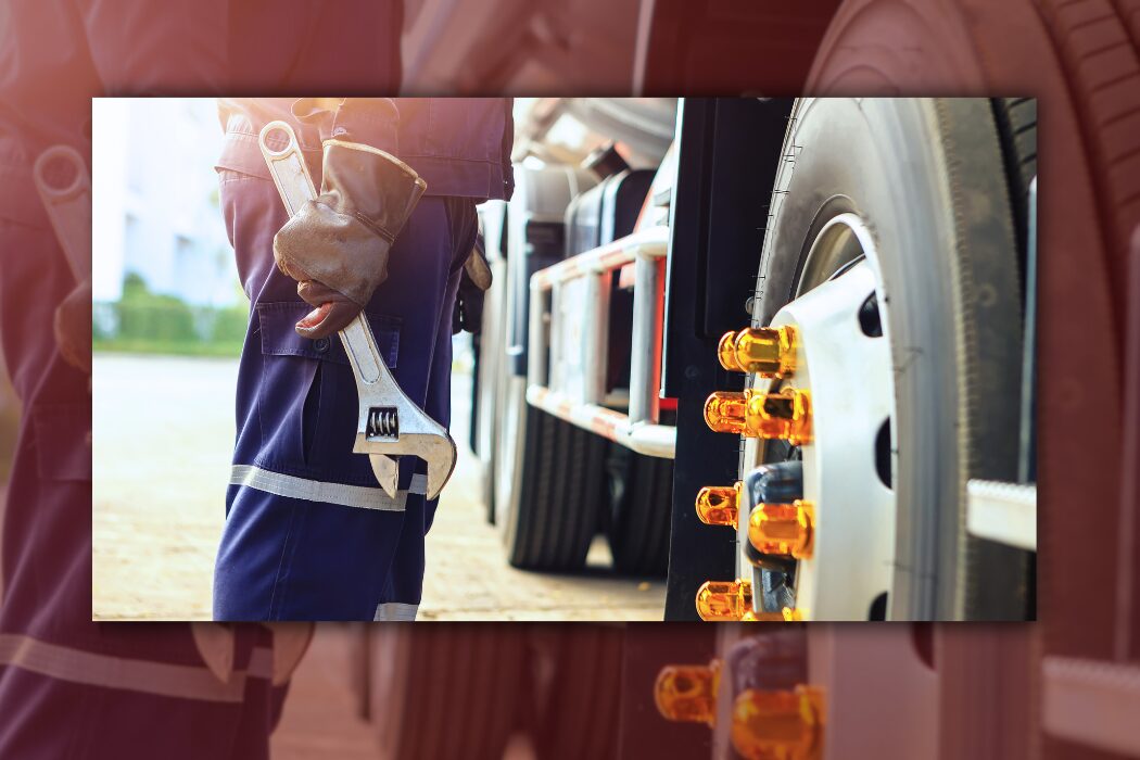 Trailer Transit Inc. | An Owner Operator in work gloves holds a large wrench next to a power-only truck, focusing on the truck’s wheel with visible lug nuts to ensure truck maintenance.
