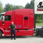 Trailer Transit Inc. | Owner Operator, Scott, stands in front of his red semi-truck, representing Owner Operator trucking in Indiana, with "Owner Operator of the Month" and "Trailer Transit Inc." logos in the top right corner.