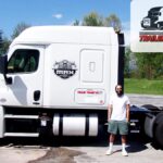 Trailer Transit Inc. | February Owner Operator of the month, Brandon, standing in front of a white semi-truck with "Trailer Transit Inc." logo, proudly recognized as the Trailer Transit Owner Operator of the Month; badge displayed in the top right corner.