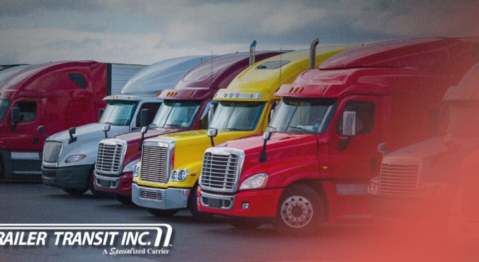 Trailer Transit Inc. | Row of semi-trucks in various colors, including red, gray, and yellow, parked side by side; "Trailer Transit Inc." logo is visible in the lower left corner—representing a truck transportation company that leases on owner operators.