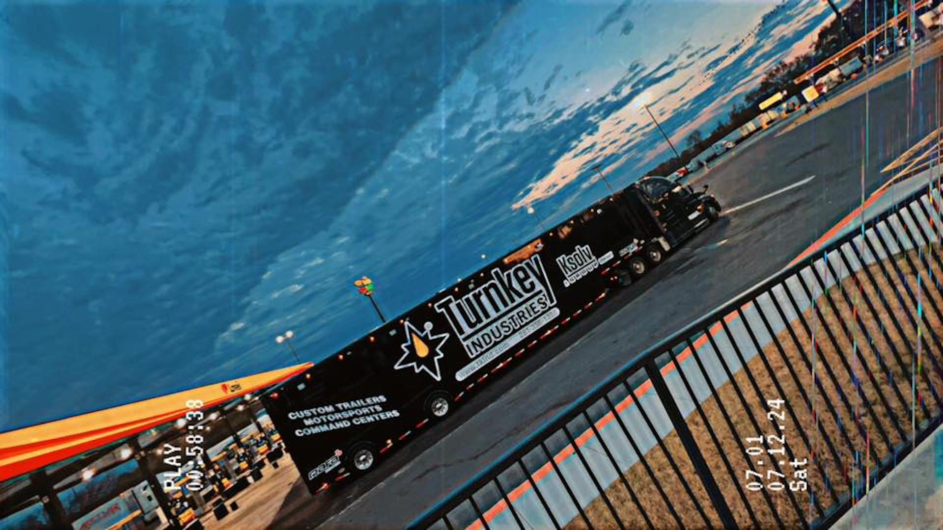 Trailer Transit, Inc. | A Turnkey Industries semi-truck is parked at a gas station under a partly cloudy sky, with time and date stamps overlaid in the foreground.
