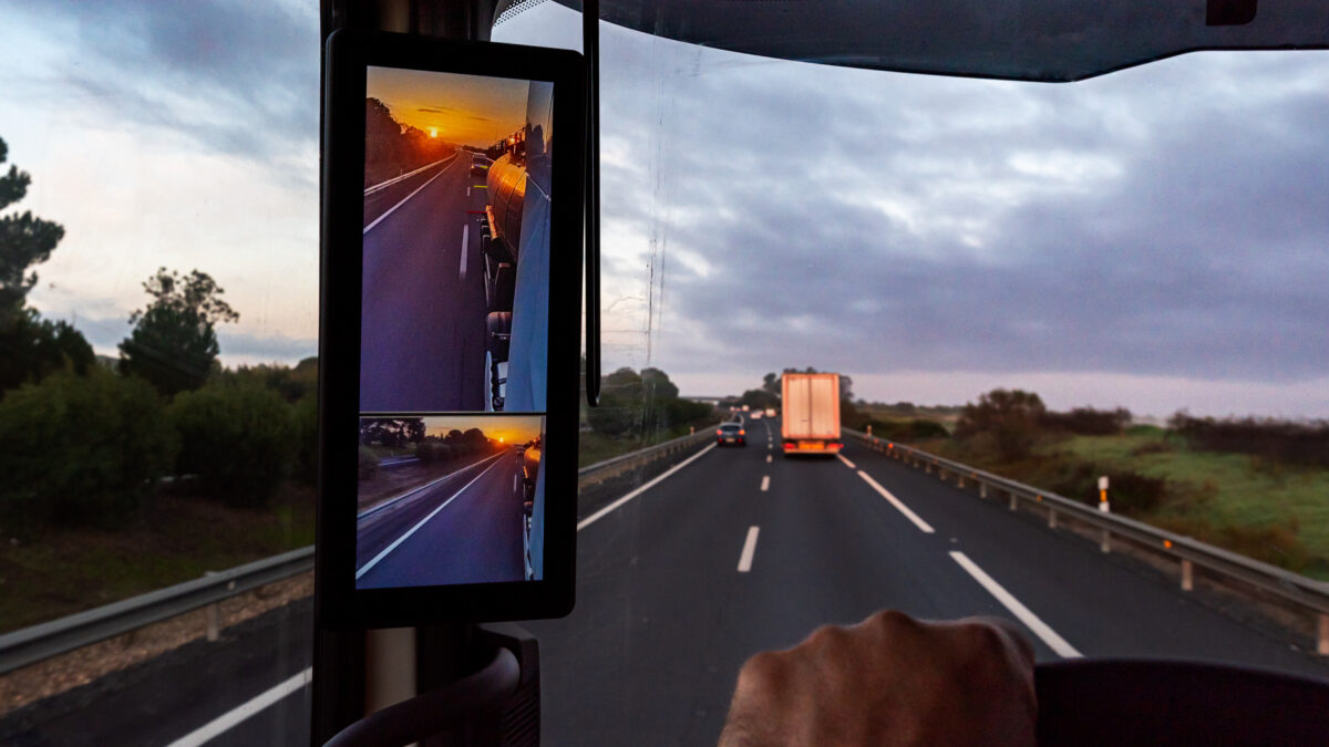 Trailer Transit, Inc. | View from the driver's position of a truck on the road of a sunrise seen by the vehicle's rearview mirrors.