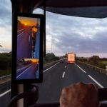 Trailer Transit, Inc. | View from the driver's position of a truck on the road of a sunrise seen by the vehicle's rearview mirrors.