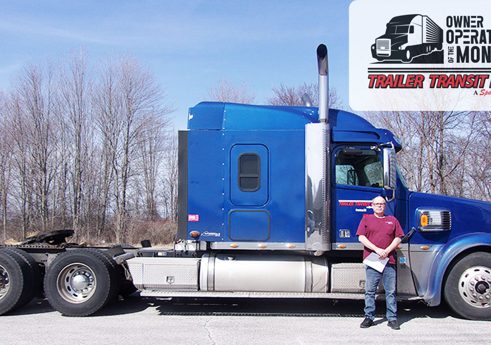 Trailer Transit, Inc. | A man stands next to a blue semi-truck. There are leafless trees in the background and a Trailer Transit Owner Operator of the Month logo in the upper right corner.